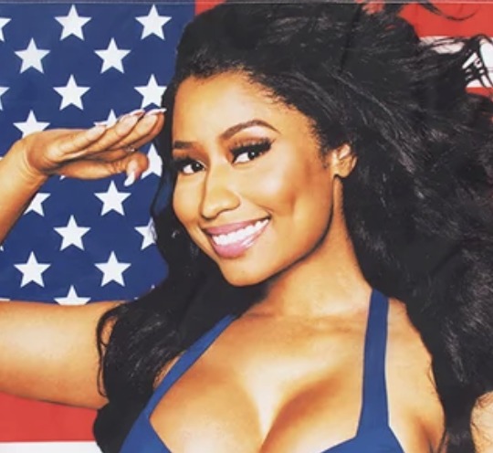 Close-up of Nicki Minaj saluting in front of an American flag